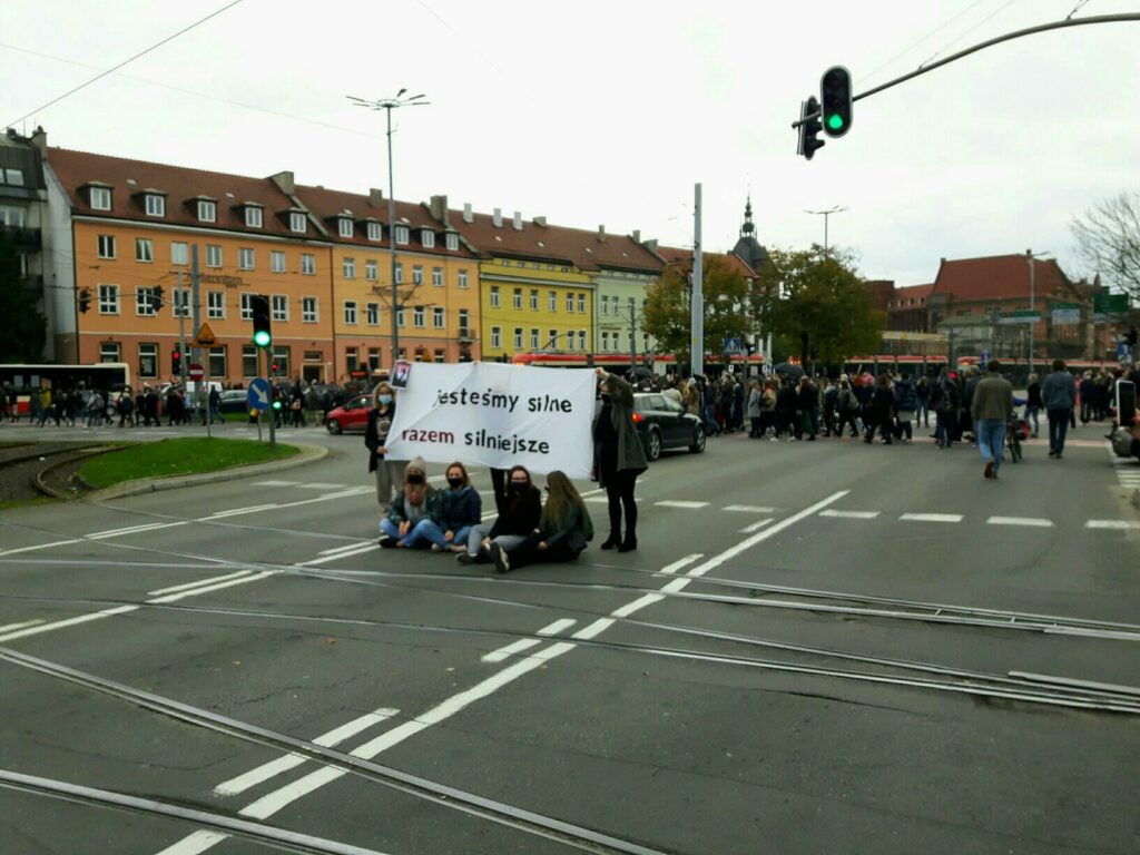 kobiety z banerem siedzą na środku ulicy w centrum gdańska