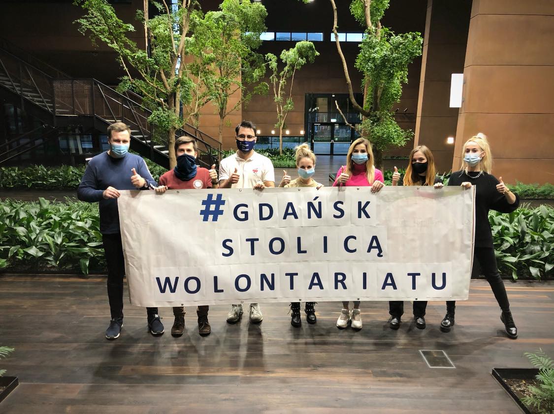Ludzie trzymają banner Gdańsk stolicą wolontariatu